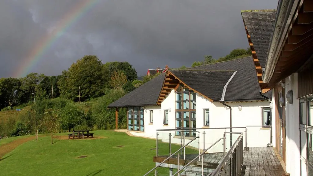 Exterior of the centre with a rainbow in the background.