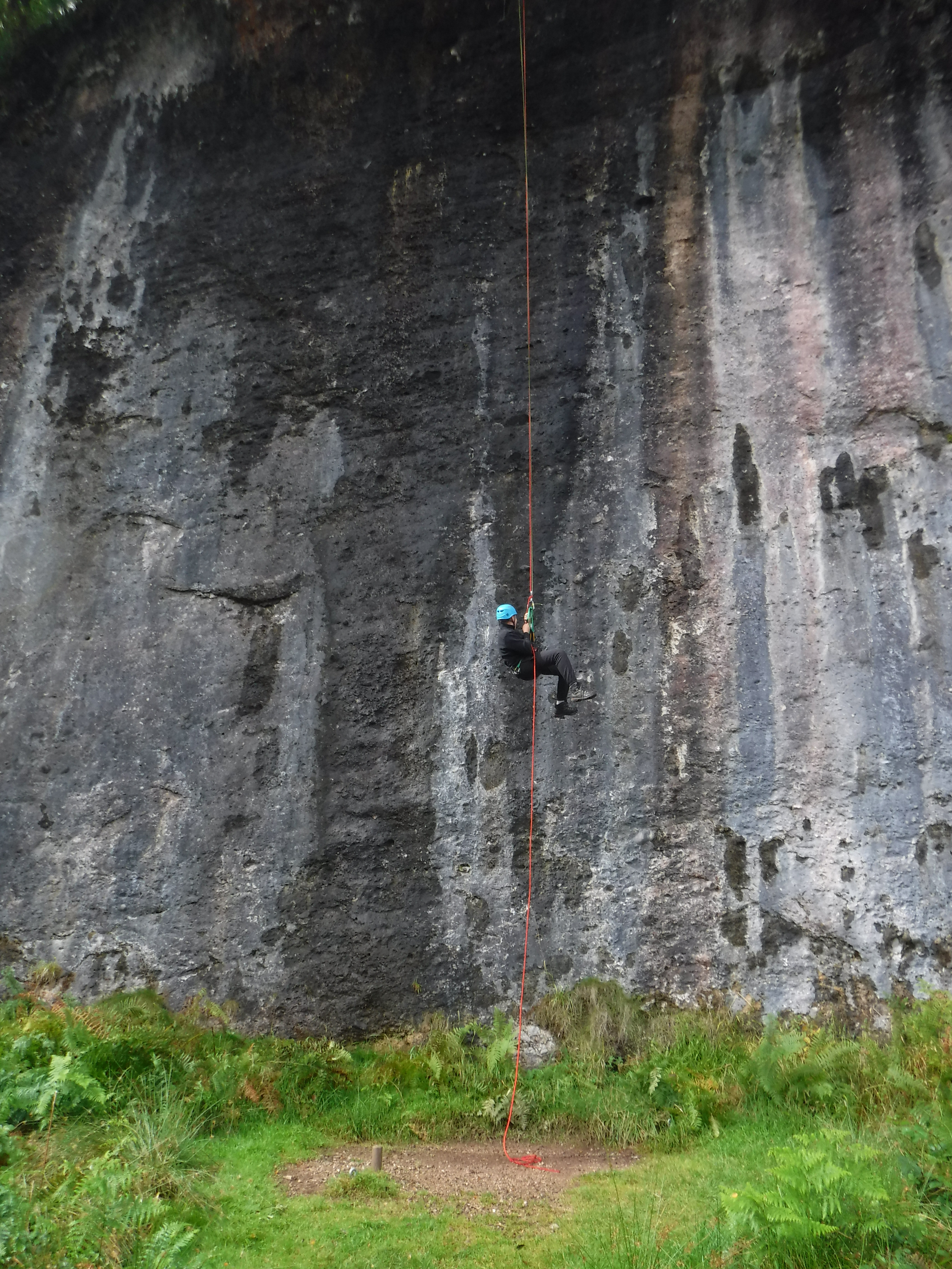 A person abseiling down a cliff face.