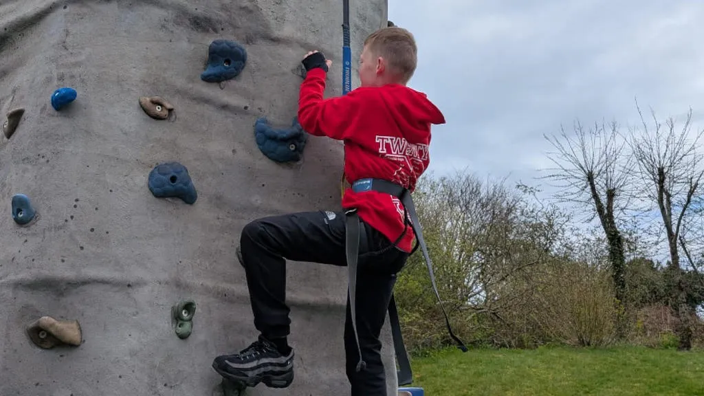 Child with safety gear on a rock climbing wall