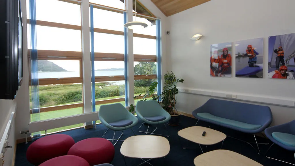 Room with large window and a selection of tables and chairs in blue red and green.