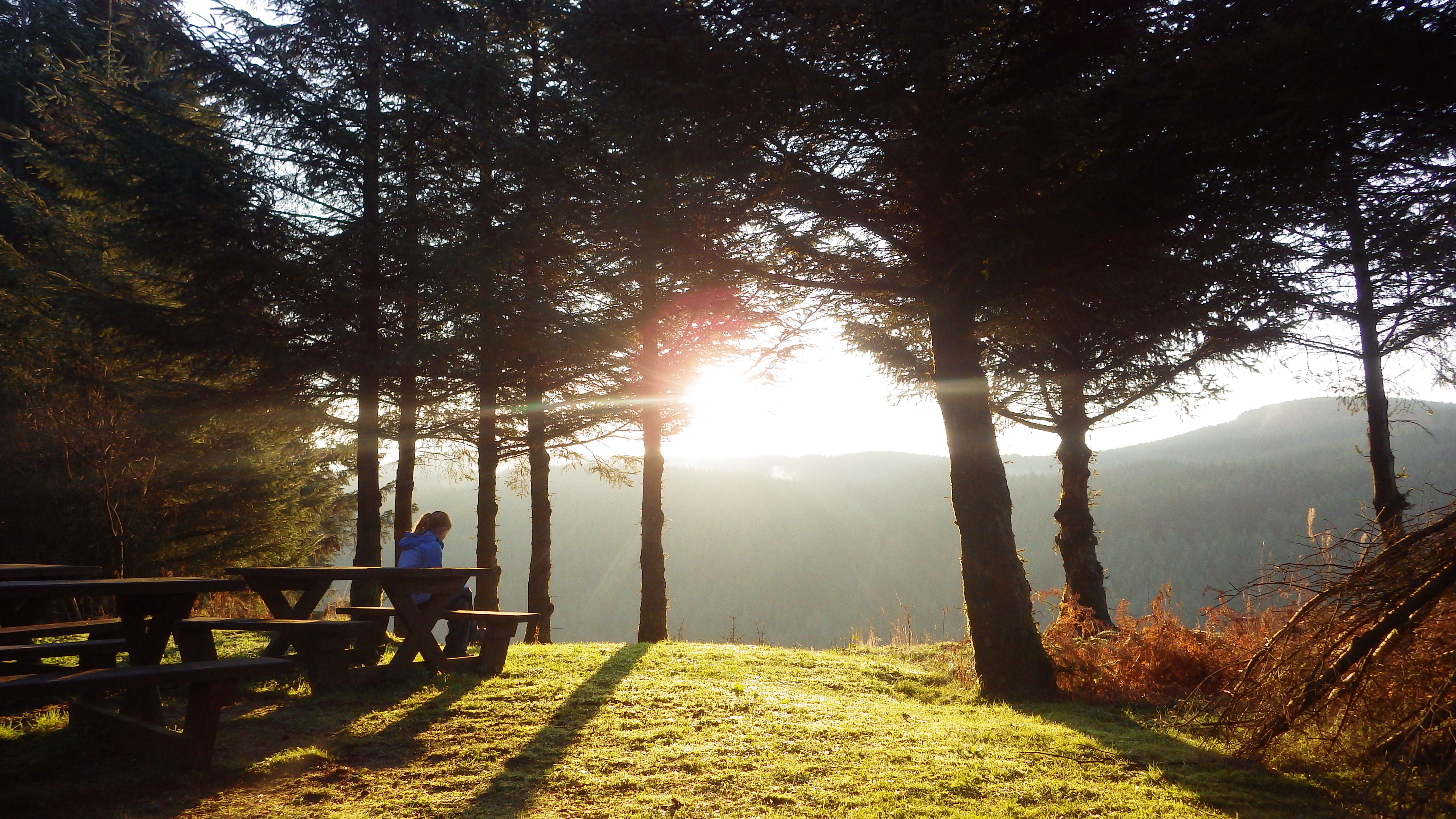 Girl on picnic bench overlooking sunset.