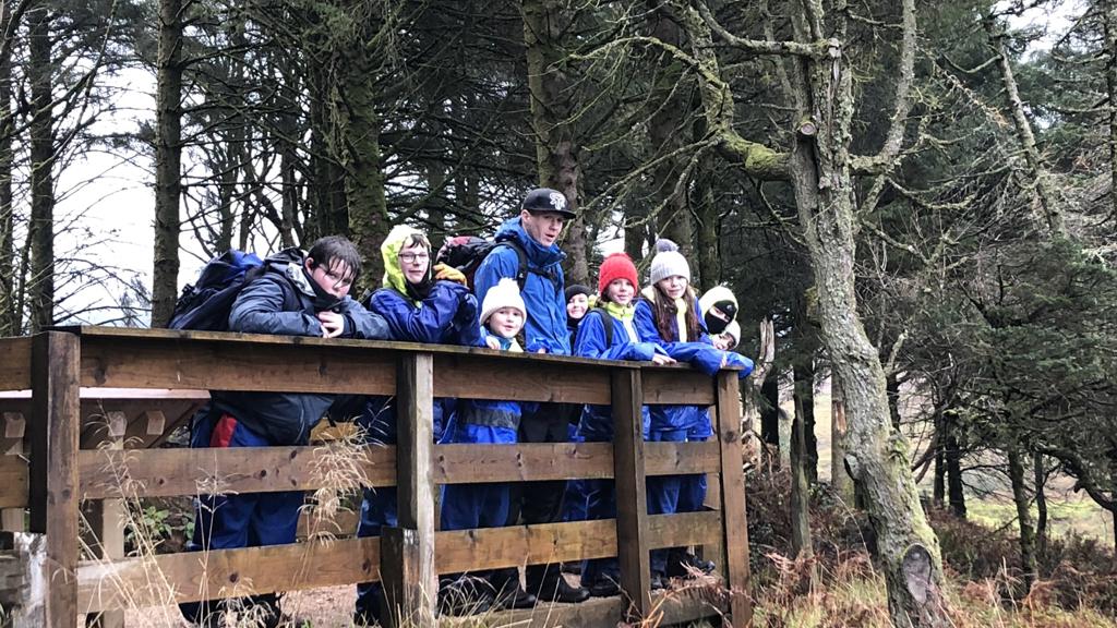 A walking group on a bridge in a forest.
