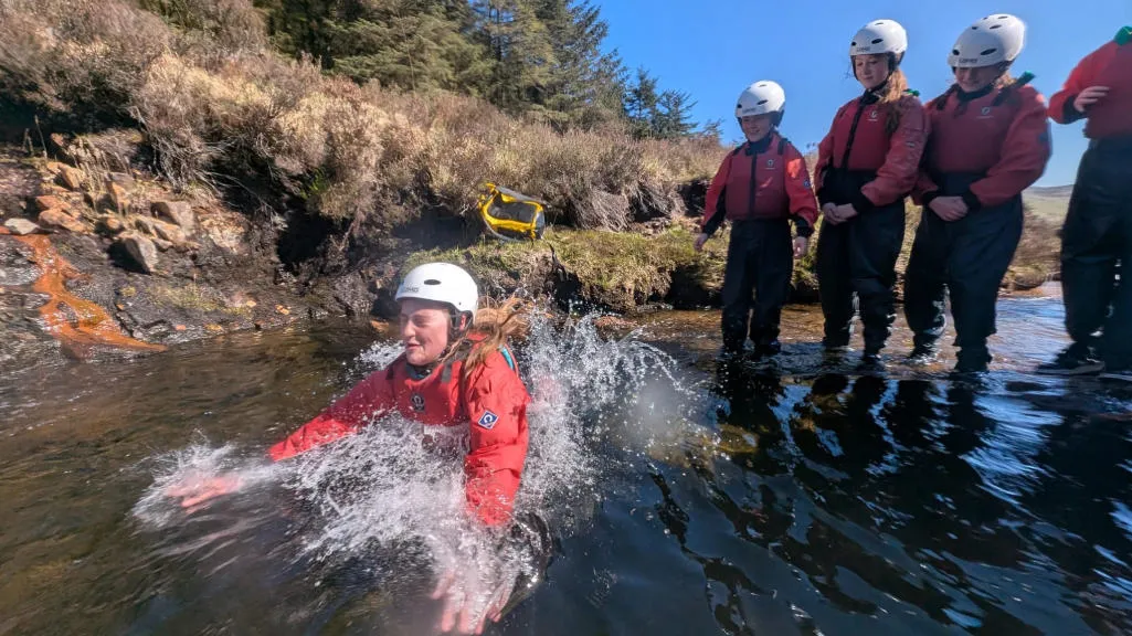 A person jumping into a rock pool, observed by a group of kids.